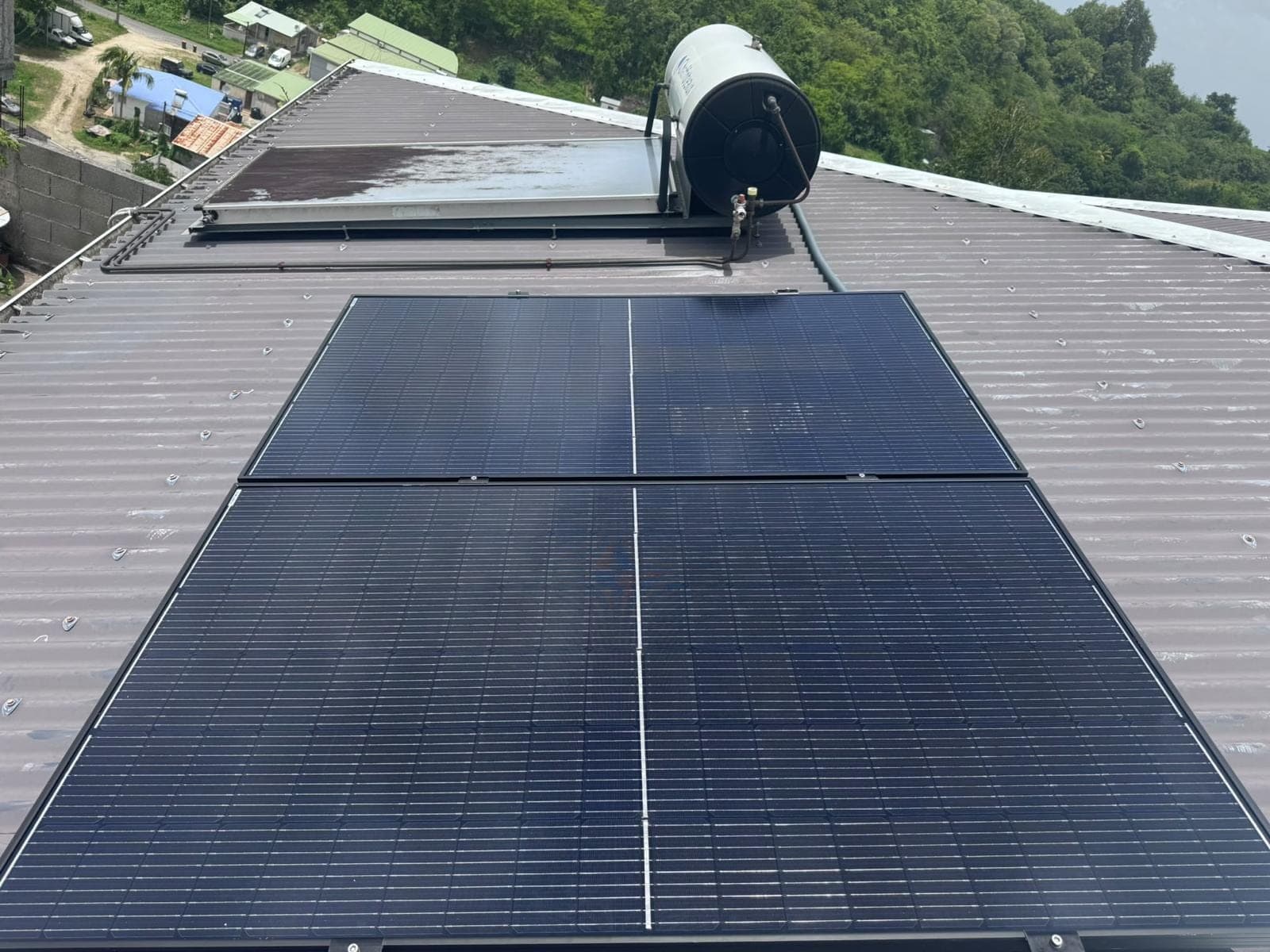 Panneaux photovoltaïques installés par FRH à côté d’un chauffe-eau solaire existant sur une toiture en Guadeloupe
