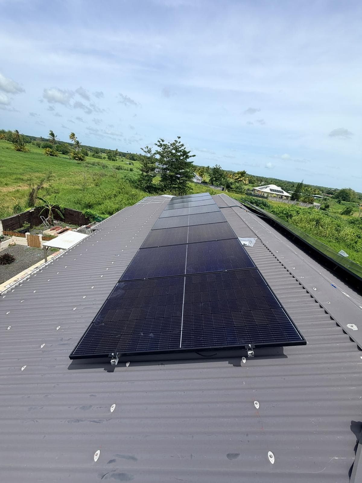 Rangée de panneaux solaires photovoltaïques sur une toiture en tôle grise en Guadeloupe